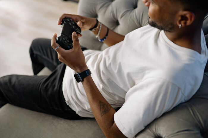 Man relaxing on couch playing video game showing laziness activity