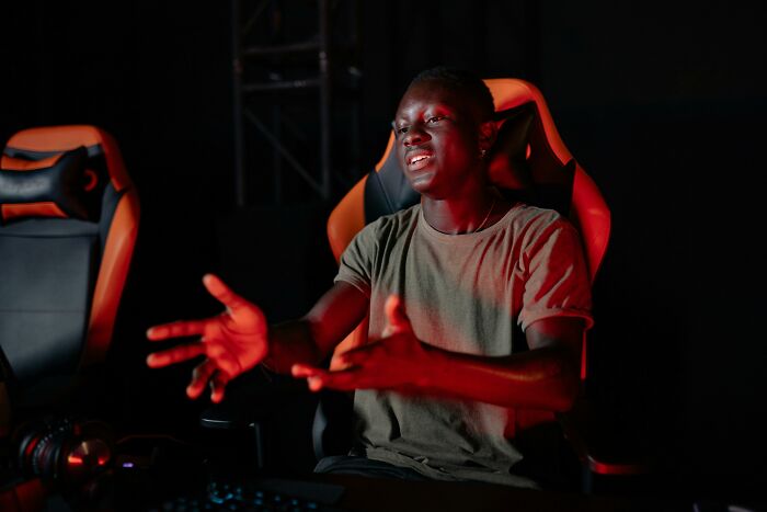 Young man animatedly speaking in a dark gaming setup