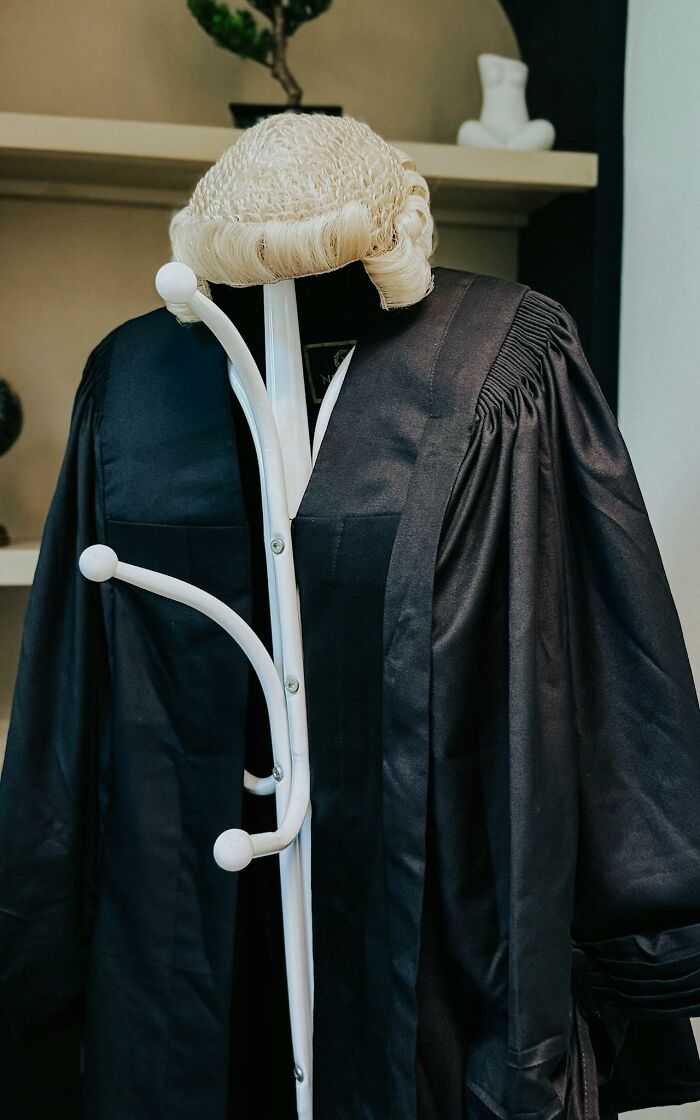 Legal wig and black robe hanging on coat rack