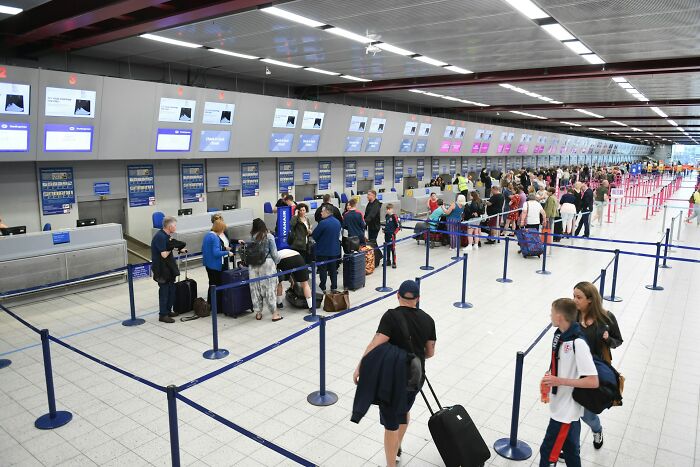 Busy airport check-in counters with travelers in line and luggage