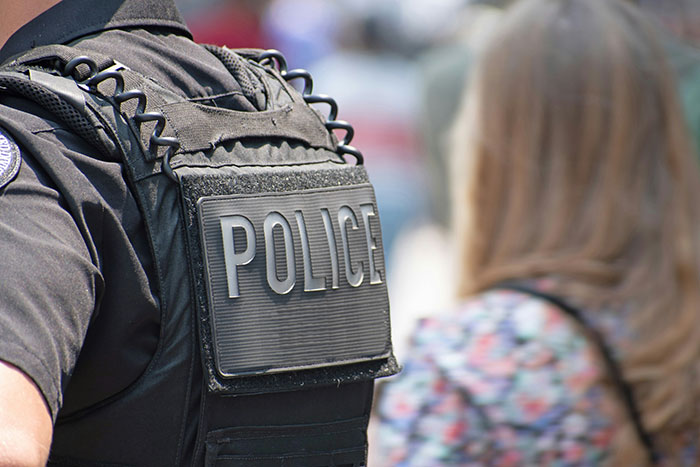 Police officer wearing a tactical vest with police badge visible Police officer wearing a tactical vest with police badge visible