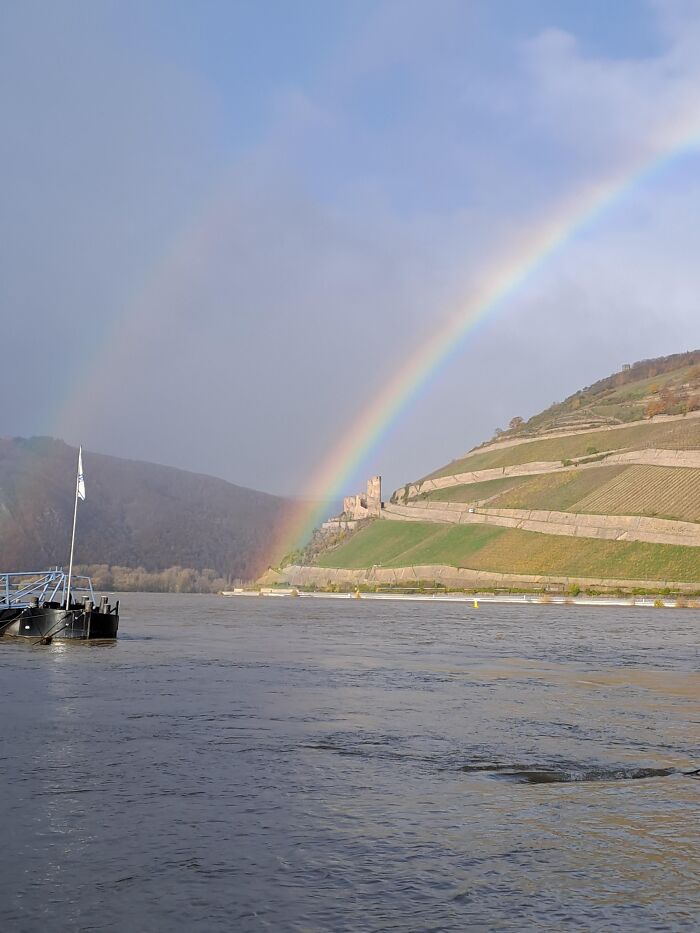 Double rainbow over river and hillside with castle ruins capturing rare moments