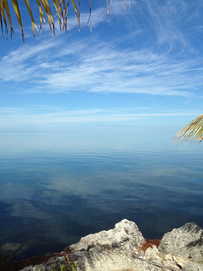 Rare moment of calm ocean with clear blue sky and rocky shoreline