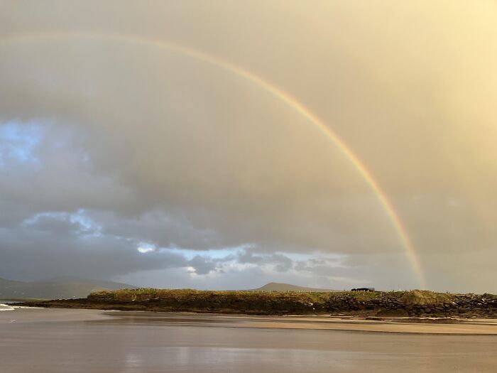 Rare moment of rainbow arching over coastal landscape