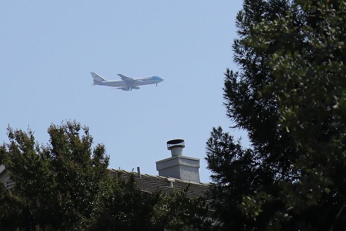 Airplane flying low above trees and houses in rare moments photo