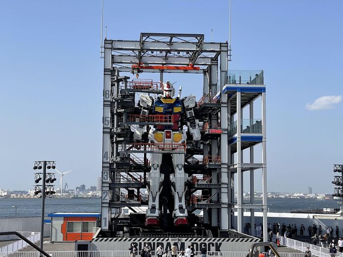 Giant Gundam robot statue at outdoor amusement park near waterfront