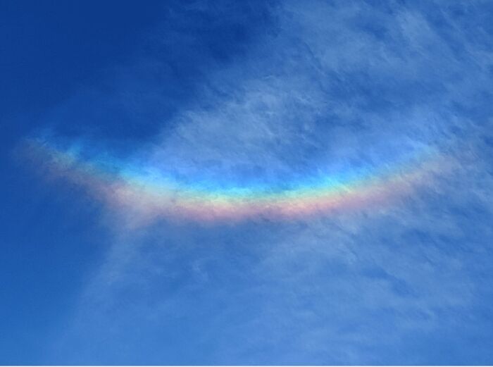 Bright rainbow-colored arc against a blue cloudy sky
