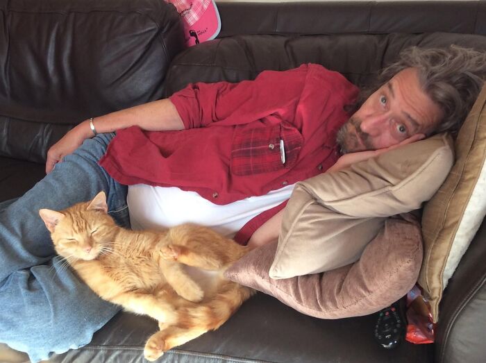 Man lying on couch with ginger cat in rare moment of relaxation