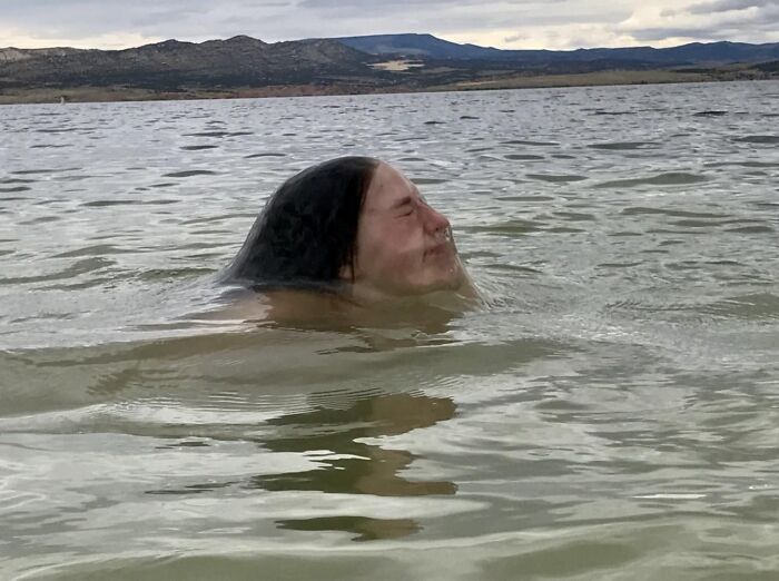 Person's head partially submerged in water creating illusion of floating hair