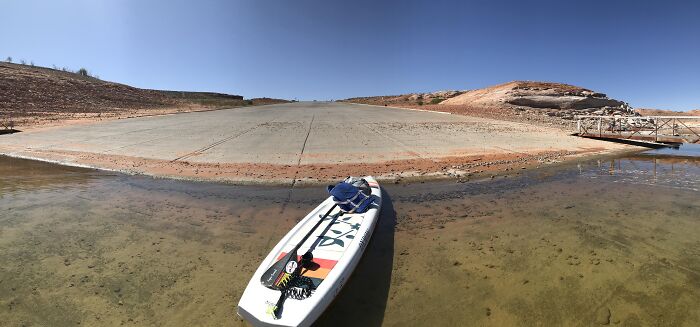 Rare moment showing paddleboard stranded on shallow lakebed with dry surroundings