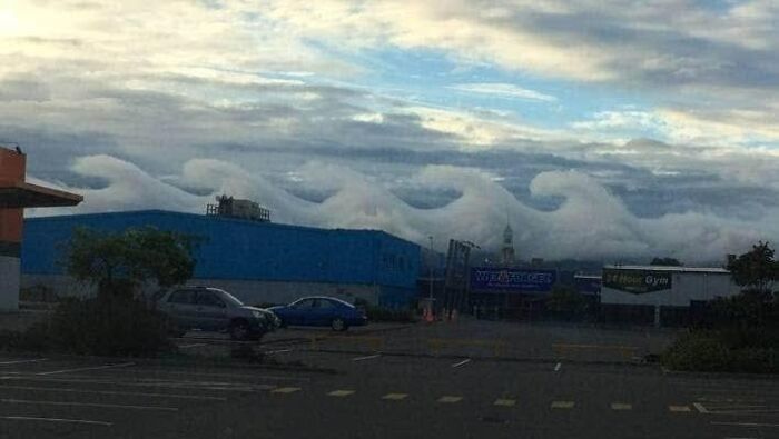 Rare photo of unusual wave-shaped clouds over a parking lot with buildings