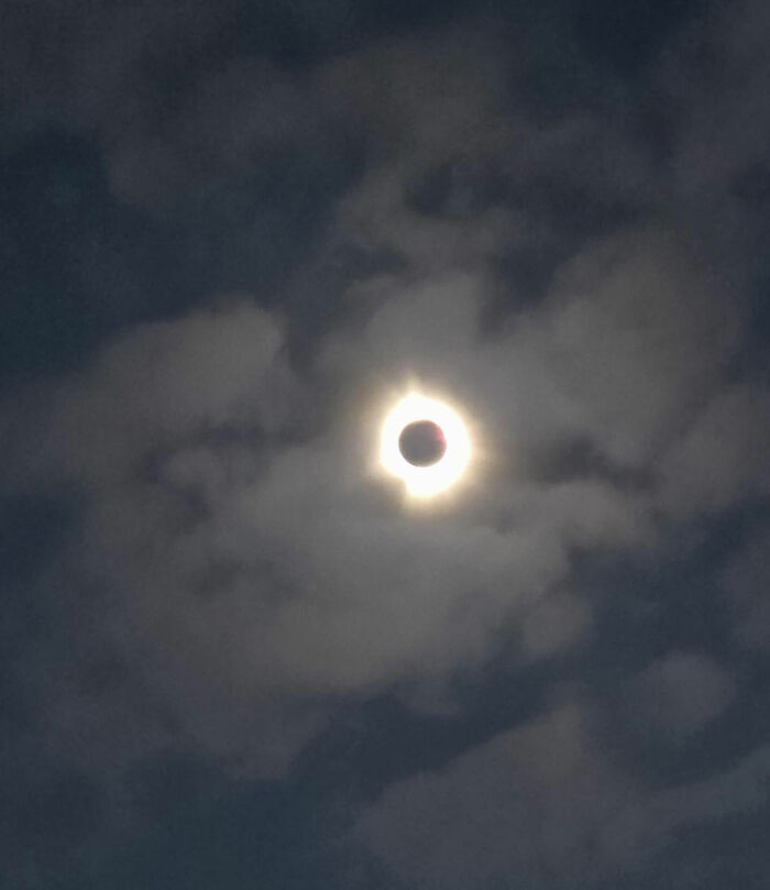 Rare moment of a solar eclipse glowing through cloudy night sky