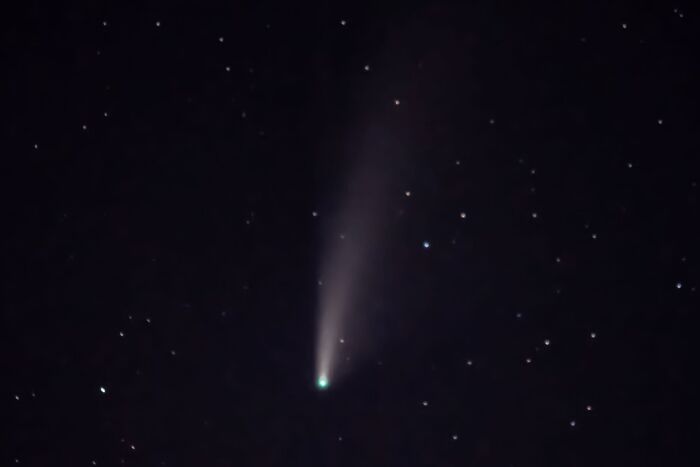 Comet with glowing tail visible in starry night sky rare moment