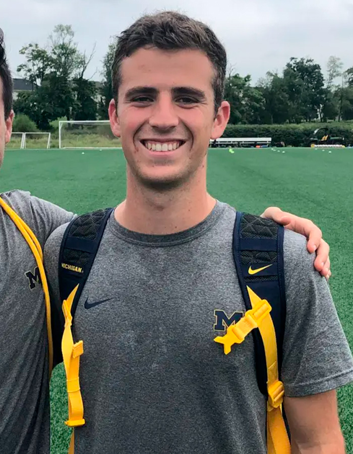 Smiling young man wearing University of Michigan shirt and backpack outdoors Smiling young man wearing University of Michigan shirt and backpack outdoors