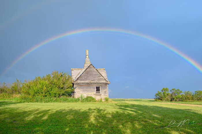 Abandoned mansion outside with double rainbow over green field