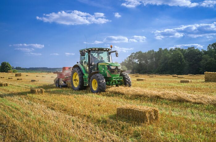 Tractor harvesting hay depicting inevitable agricultural challenges