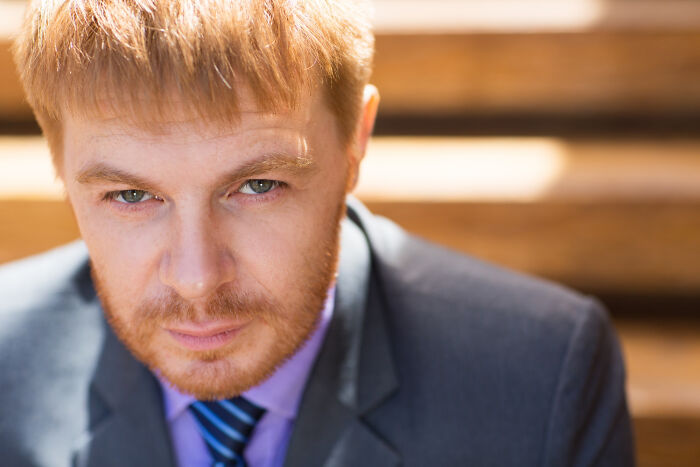 A man with ginger hair and beard, wearing a suit and tie, looking intently. Reveals more about someone. Red flags.