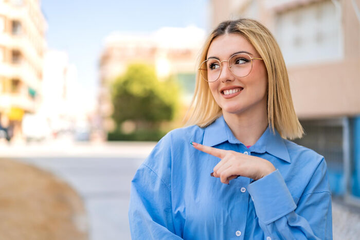 A smiling blonde woman with glasses points to the left, showing tiny red flags that reveal more about someone.