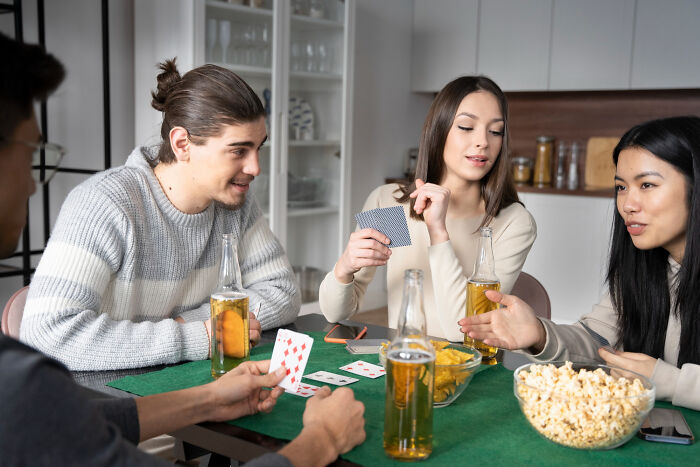Friends playing cards at home, with beer and snacks, revealing tiny red flags about their personalities.