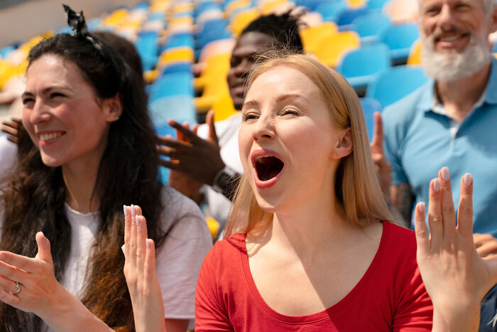 A diverse group of cheering spectators, highlighting emotional expression. Reveals more about someone from tiny red flags.