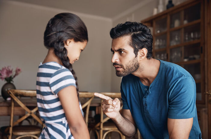 A stern man scolding a young girl, who looks downcast. A tiny red flag regarding communication styles.