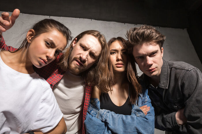 Four young adults look down at the camera with serious, skeptical expressions, hinting at tiny red flags.