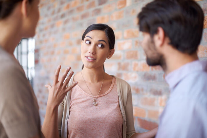 A woman, expressing herself with hand gestures, engages in conversation with two others, revealing tiny red flags about someone.