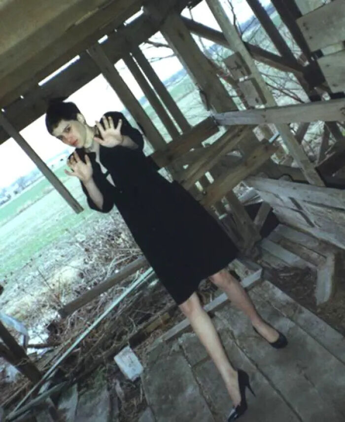 Creepy photo of woman in black dress with distorted posture outdoors