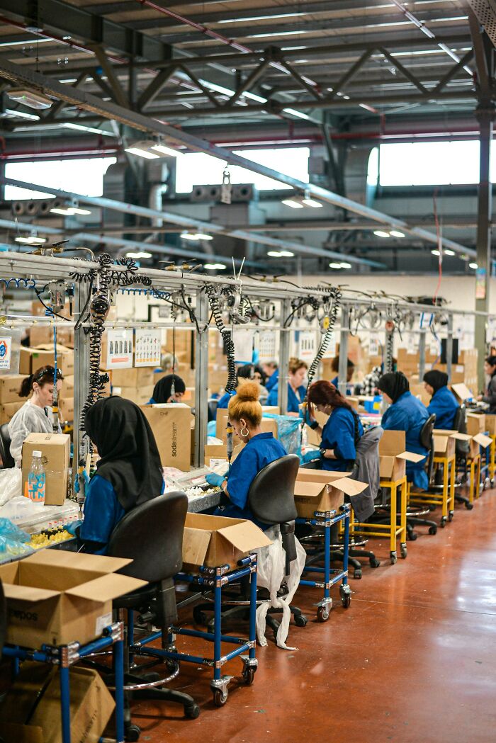 Employees in a large factory assemble products along a conveyor belt, illustrating industry secrets.