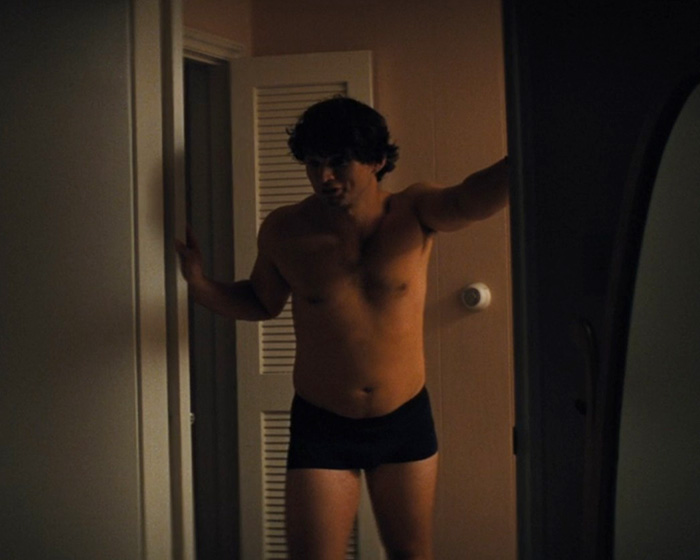 Shirtless man in black underwear standing in dimly lit room doorway Shirtless man in black underwear standing in dimly lit room doorway