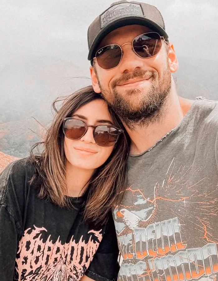 Rockstar and wife smiling together outdoors wearing sunglasses Rockstar and wife smiling together outdoors wearing sunglasses