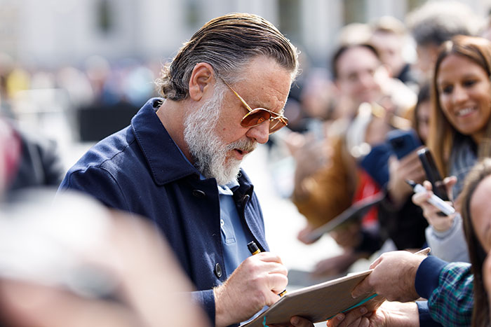 Russell Crowe signing autographs for fans outdoors during public event
