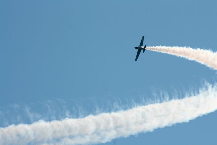 Airplane performing stunt with smoke trail in clear blue sky