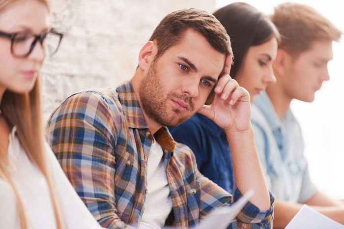 Pensive young man reading in study group Pensive young man reading in study group