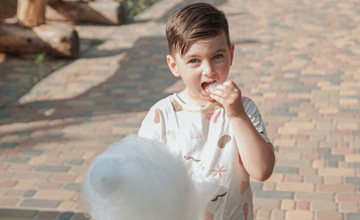 A young boy happily eating cotton candy, challenging outdated facts about childhood treats.