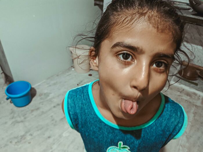 A young girl in a blue shirt sticking her tongue out, looking at the camera. Exploring outdated facts and common misconceptions.