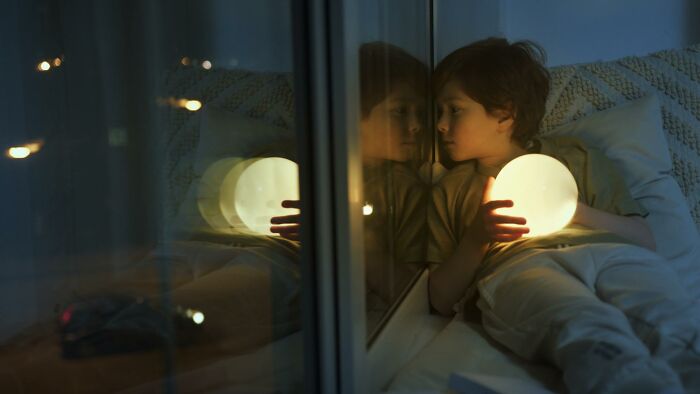 A young child holding a glowing orb while resting. The image reflects an outdated fact about nightlights.