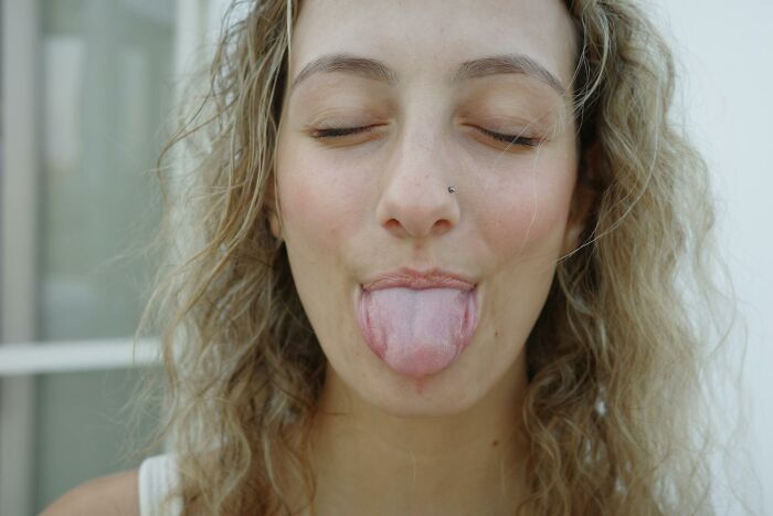 A young woman with curly blonde hair, eyes closed, sticking her tongue out, conveying a playful attitude about outdated facts.