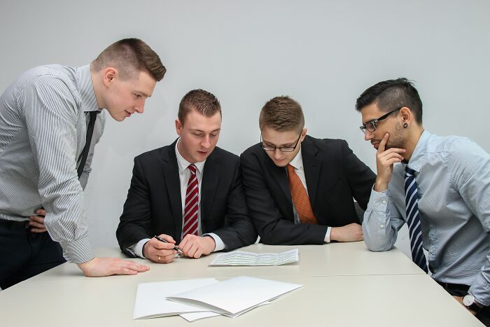 Group of businessmen reviewing documents about peace over paycheck quitting scenarios