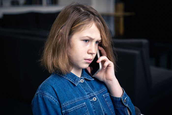 Young girl in denim jacket worried while talking on phone about escaping a cult