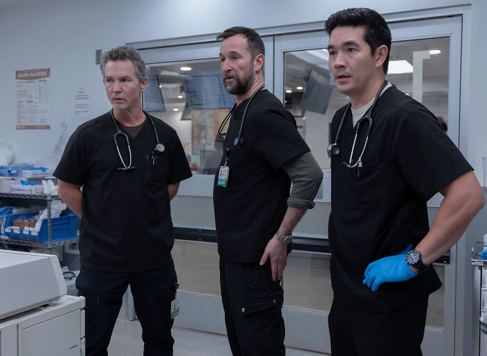 The Pitt doctors in black scrubs discussing a medical case The Pitt doctors in black scrubs discussing a medical case