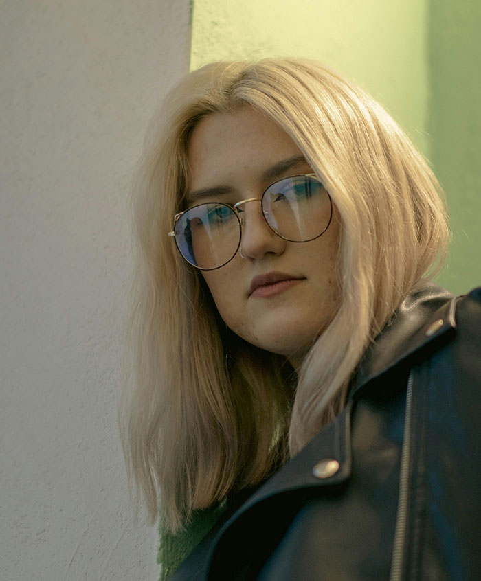 Woman with blonde hair wearing glasses and leather jacket beauty portrait