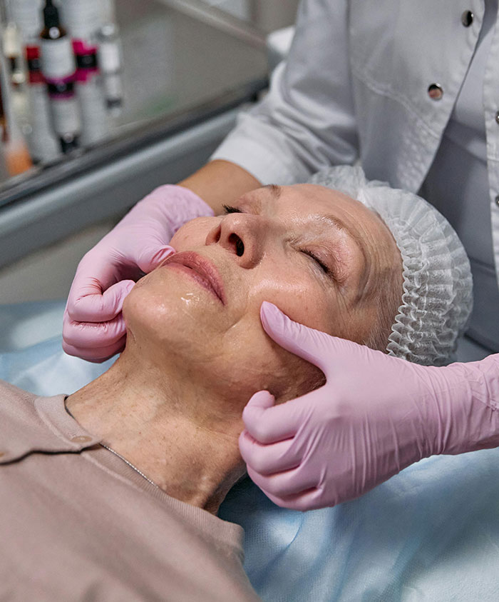 Woman receiving facial treatment from esthetician wearing gloves beauty care