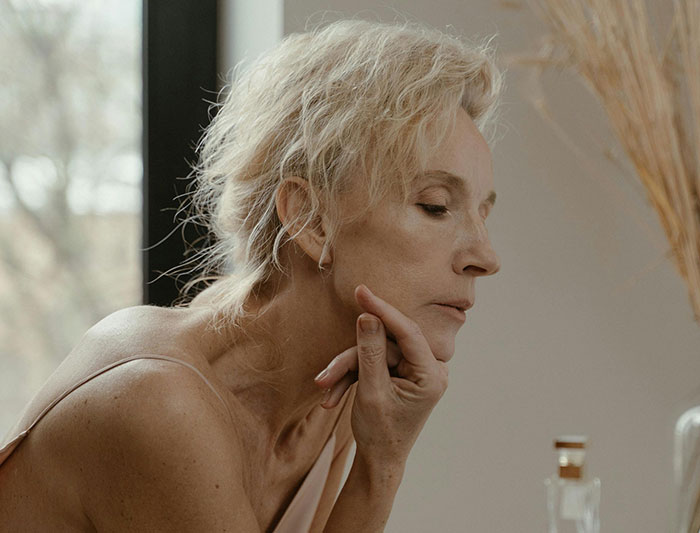 Older woman with light hair resting chin on hand beauty profile