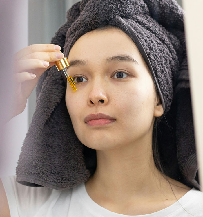 Woman applying facial serum for skincare beauty lies