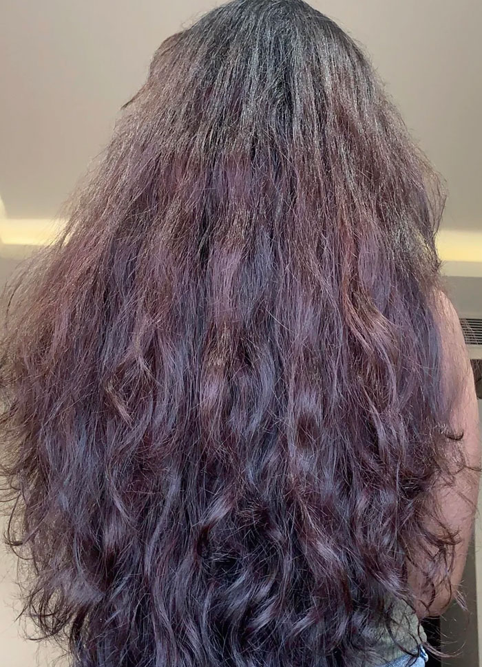 Back view of woman with long wavy hair indoors hair care beauty lies uncovered