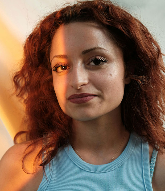 Red-haired woman in blue top illuminated by sunlight beauty shot