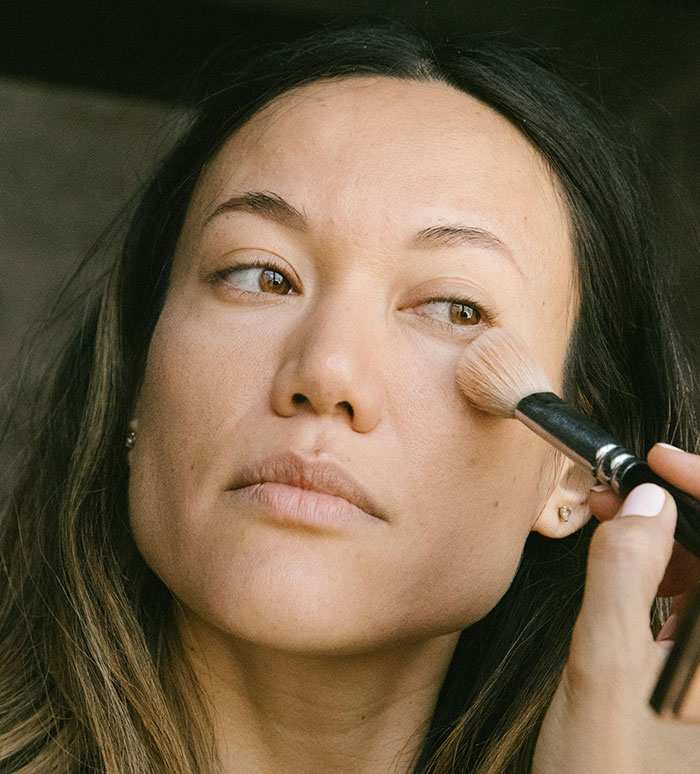 Woman applying makeup with brush close-up beauty routine
