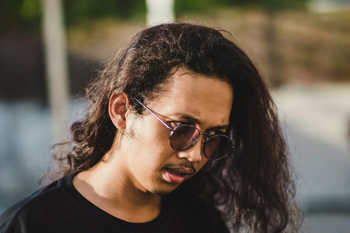 Man with sunglasses looking down, showing a reflective moments in a situationship