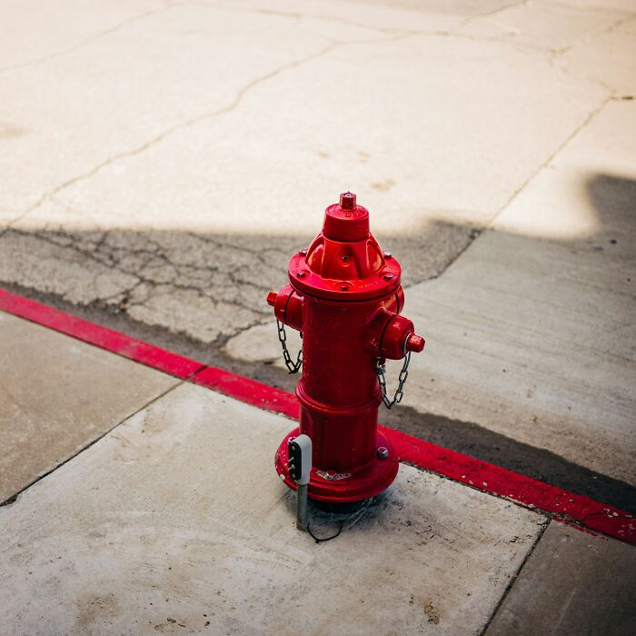 Red fire hydrant on cracked pavement near a red curb line